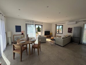 A modern living room with a dining area, a sofa set, a TV, and a refrigerator. - Villa South Side - private pool (L'Isle-sur-la-Sorgue)