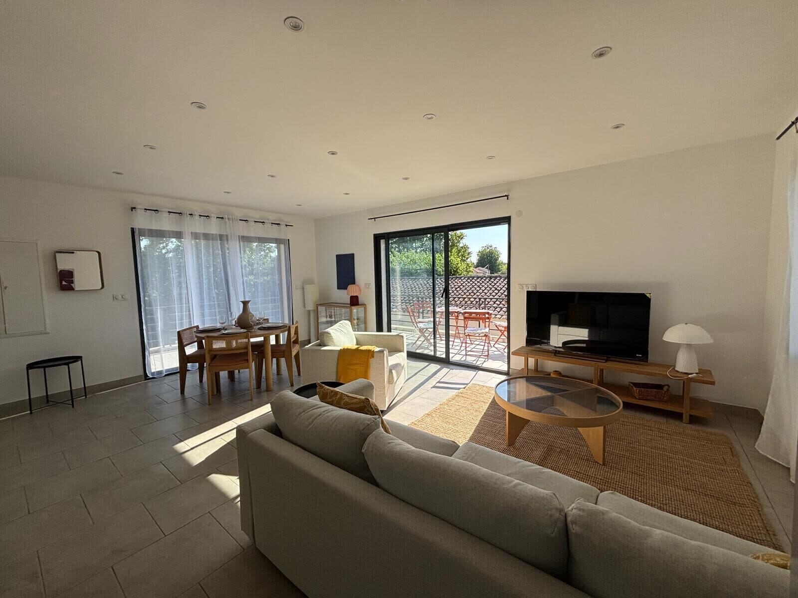 A modern living room with a sofa, TV, and dining area.
