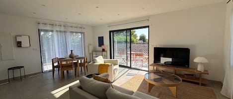 A modern living room with a sofa, TV, and dining area.