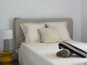 A bed with a beige headboard, two pillows, a rolled blanket, and a bedside table with a lamp. - Solea - Terrace Side (L'Isle-sur-la-Sorgue)