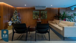 Una sala de estar moderna con un árbol de Navidad, un sofá, dos sillones y una mesita.