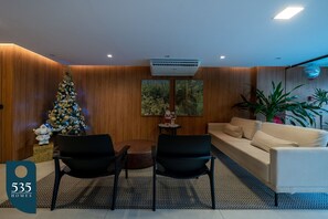 Ein modernes Wohnzimmer mit Weihnachtsbaum, einer Couch, zwei Sesseln und einem kleinen Tisch.