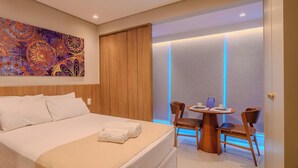 Habitación de hotel con cama, una mesa y sillas, un cuadro en la pared y ventana con vistas.