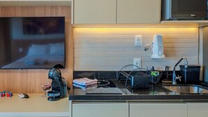 Una cocina moderna con televisor de pantalla plana, cafetera y microondas.