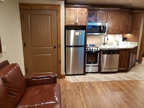 Una cocina con electrodomésticos de acero inoxidable, armarios de madera y un sofá de cuero marrón.