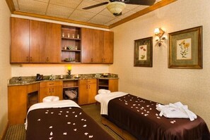 Ein Zimmer mit zwei Betten, Holzschränken, einer Theke mit Spüle und gerahmten Blumenbildern an der Wand.