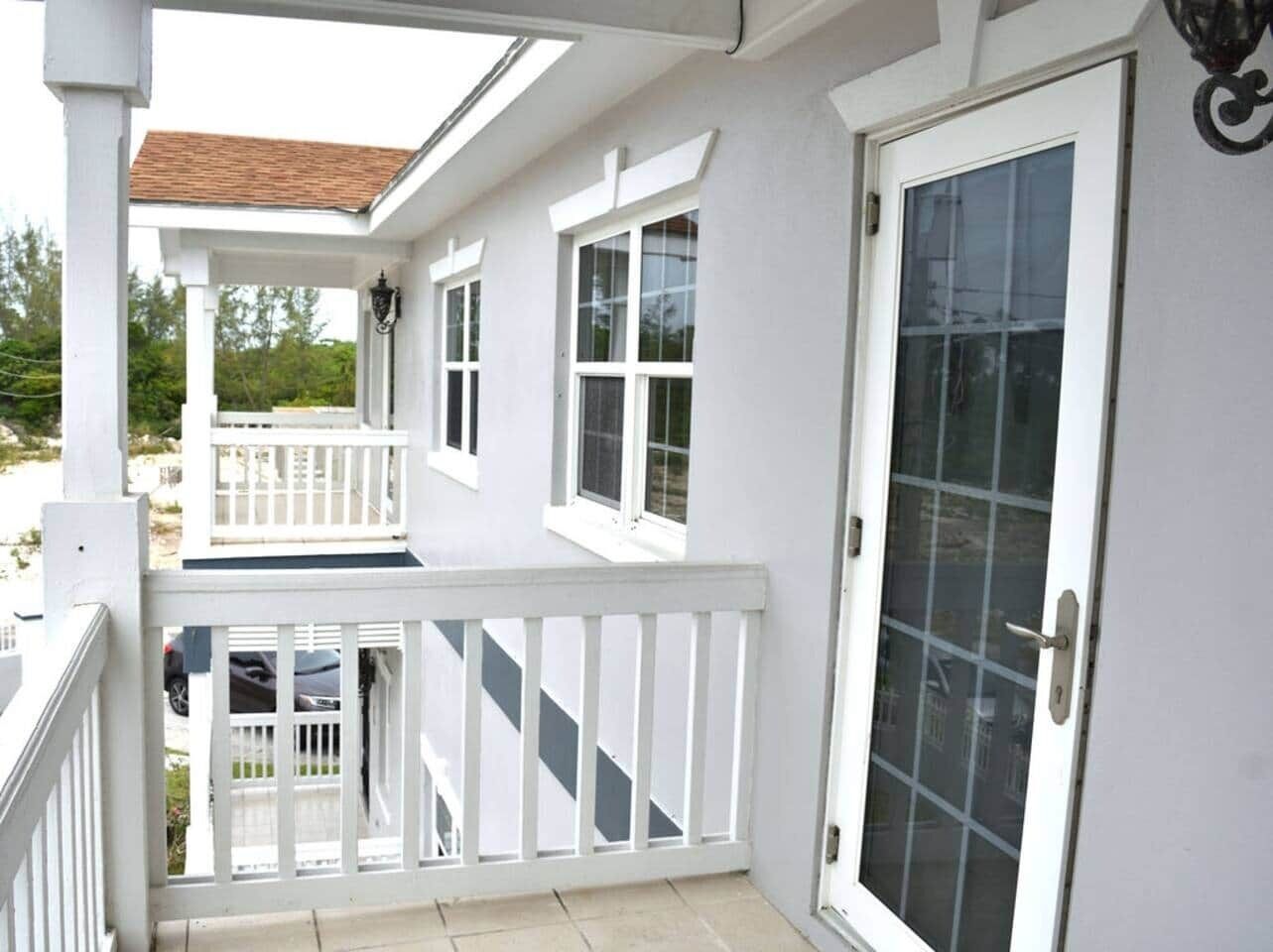 A two-story building with a balcony, a door with a glass panel, and a window.