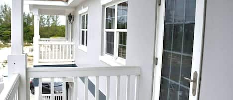A two-story building with a balcony, a door with a glass panel, and a window.