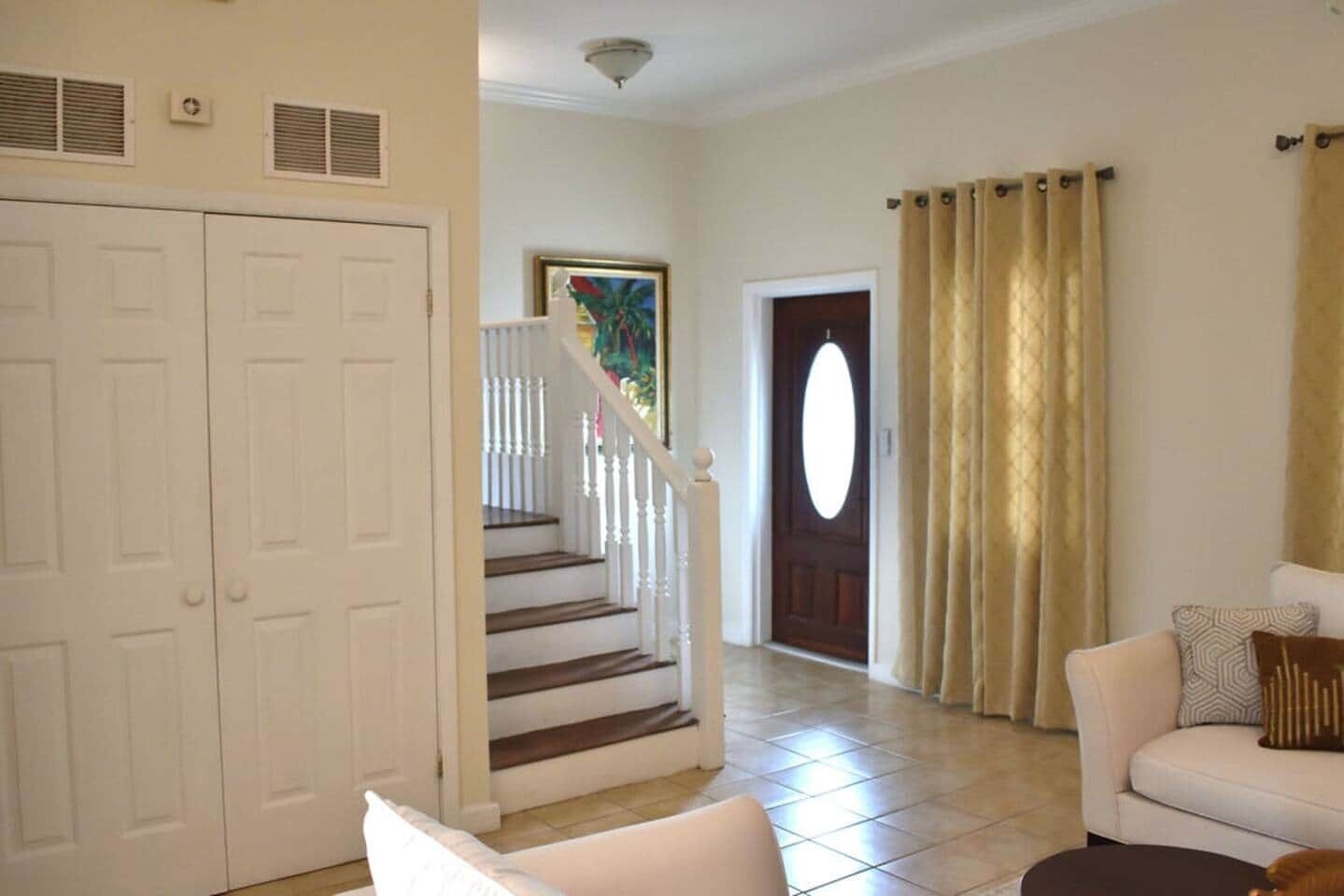 A living room with a sofa, a coffee table, and a staircase leading to a door.