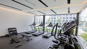 A gym with treadmills, a bench, and dumbbells. - First-floor apartment with pool view (Punta Cana)