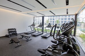 Ein Fitnessraum mit Laufbändern, einer Bank und Kurzhanteln.