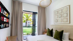 A hotel room with a bed, pillows, a nightstand, a lamp, a framed picture, and a curtain. - First-floor apartment with pool view (Punta Cana)