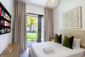 Ein Hotelzimmer mit Bett, Kissen, Nachttisch, Lampe, einem gerahmten Bild und einem Vorhang.