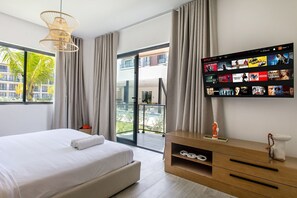 Ein modernes Hotelzimmer mit einem großen Bett, einem an der Wand montierten Fernseher, der eine Auswahl an Filmen zeigt, und einem Balkon mit Blick auf die Stadt.
