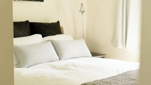 Ein Schlafzimmer mit einem Bett, Kissen, einem Nachttisch, einer Lampe und einem Bild an der Wand.