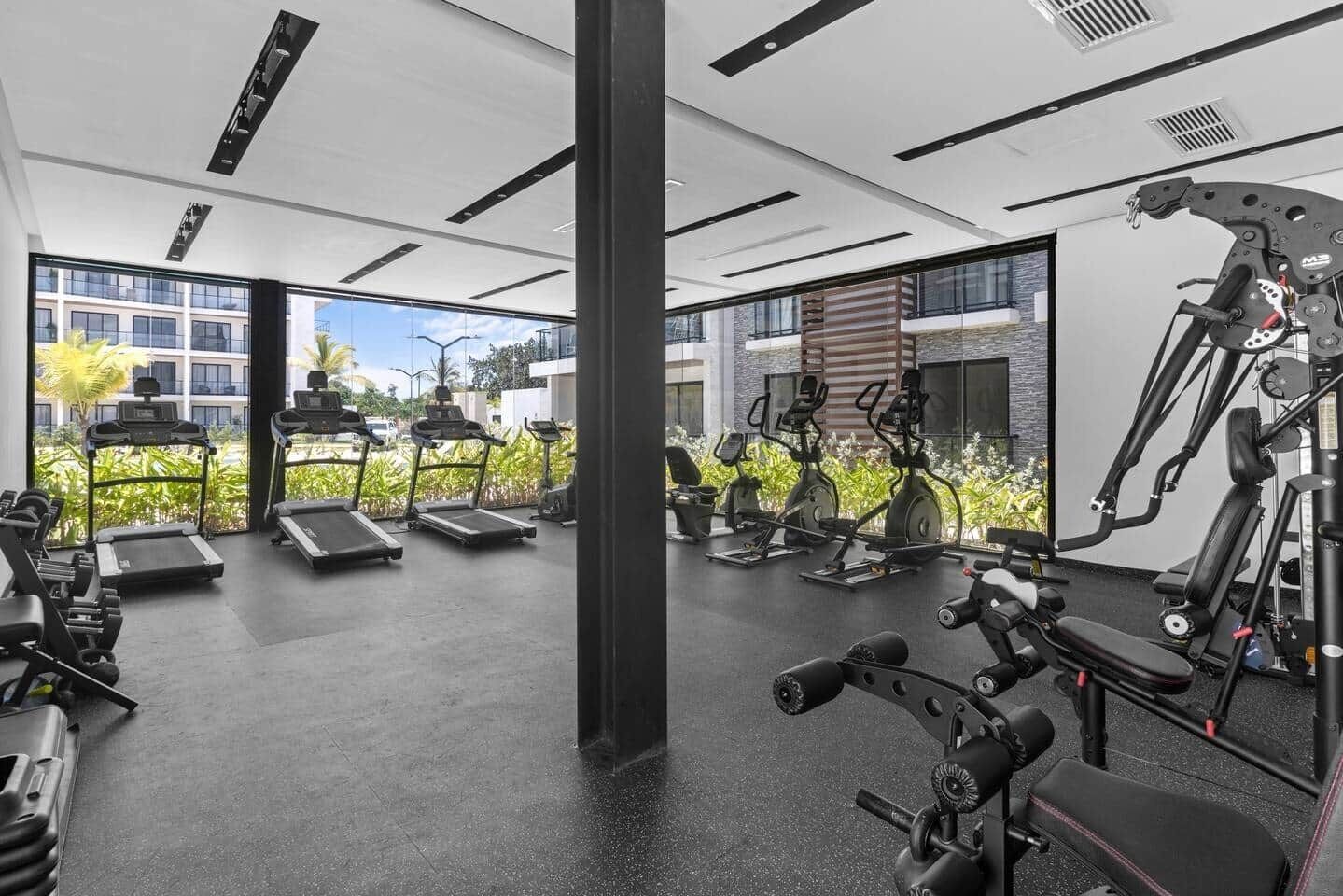 A modern gym with treadmills, elliptical machines, and weightlifting equipment.