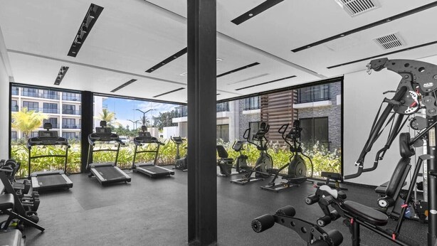 A modern gym with treadmills, elliptical machines, and weightlifting equipment. - New Luxury Condo | Pool View | Minutes to Beach (Punta Cana)