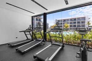 Un gimnasio con cintas de correr, bicicletas estáticas y una máquina de remo.