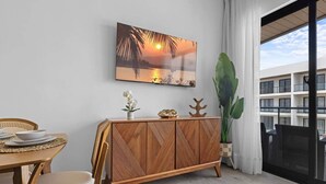 A dining area with a wooden table, chairs, a buffet cabinet, and a large potted plant. - New Luxury Condo | Pool View | Minutes to Beach (Punta Cana)