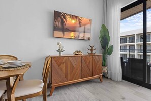 Uma área de refeições com mesa de madeira, cadeiras, aparador e uma grande planta em vaso.