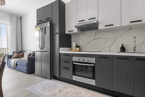 A modern kitchen with a built-in oven, a stainless steel refrigerator, and a marble backsplash. - New Luxury Condo | Pool View | Minutes to Beach (Punta Cana)