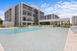 Um edifício moderno com piscina e espreguiçadeiras.