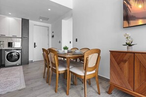 Uma cozinha moderna com máquina de lavar roupa, uma área de refeições com mesa redonda e cadeiras, e um armário decorativo.