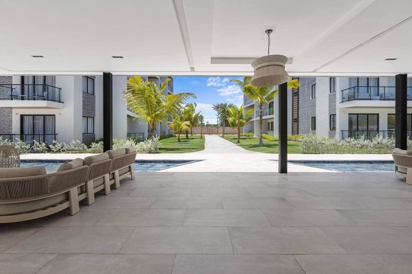 A modern hotel lobby with a pool, seating areas, and a view of the pool.