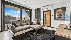 Ein modernes Wohnzimmer mit einem Ecksofa, einem schwarzen, flauschigen Teppich und einem Holztisch.