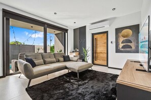 A modern living room with a sectional sofa, a black furry rug, and a wooden desk. - Luxurious Apartment with Private Pool (Oranjestad)