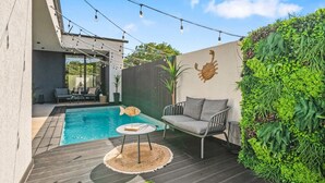 Eine moderne Außenpatio mit Pool, Sitzbereich und dekorativer Wand.