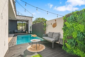 A modern outdoor patio with a pool, a seating area, and a decorative wall. - Luxurious Apartment with Private Pool (Oranjestad)