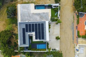 Ein modernes Gebäude mit Pool auf dem Dach, Solaranlagen und einem gepflegten Rasen.
