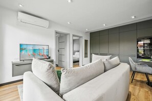 Ein modernes Wohnzimmer mit einer Couch, einem Flachbildfernseher und einem Essbereich mit Tisch und Stühlen.