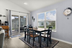 A dining area with a table and chairs, a coffee bar, and a clock on the wall. - Bright & Pet-Friendly Cottage Home in the Village of Well Point (Sumterville)