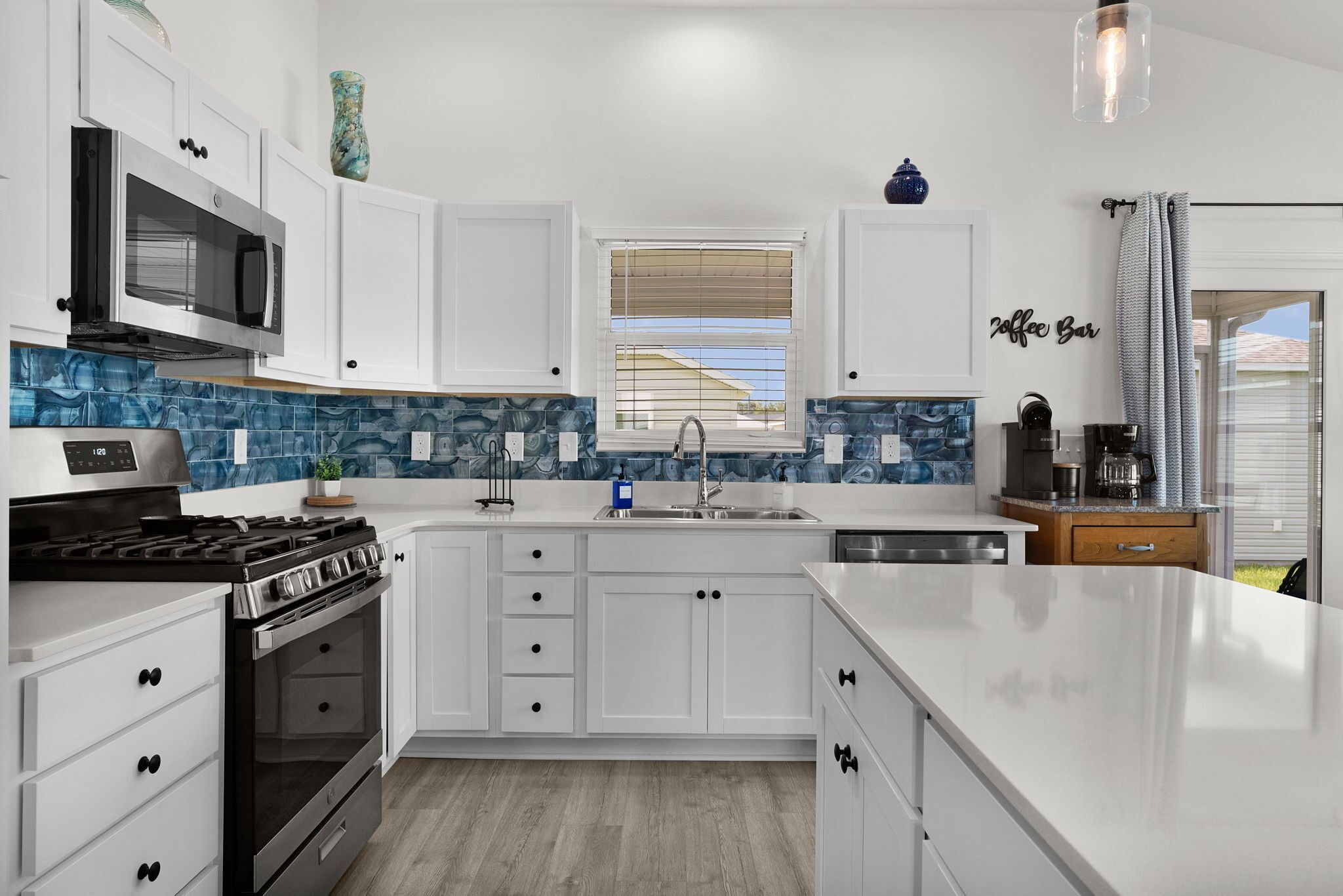 A modern kitchen with white cabinetry, a stainless steel stove, and a blue-tiled backsplash.