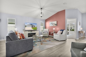 A modern living room with a fireplace, a television, and a dining area. - Bright & Pet-Friendly Cottage Home in the Village of Well Point (Sumterville)