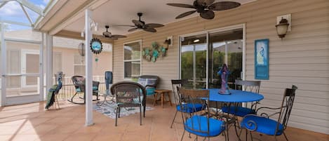 Un patio cubierto con ventiladores de techo, asientos exteriores y una estatua decorativa de un pavo real.