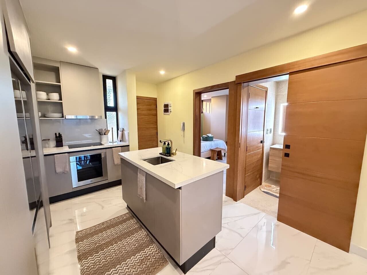 Een moderne keuken met een centraal eiland, een ingebouwde oven en een eethoek met uitzicht.