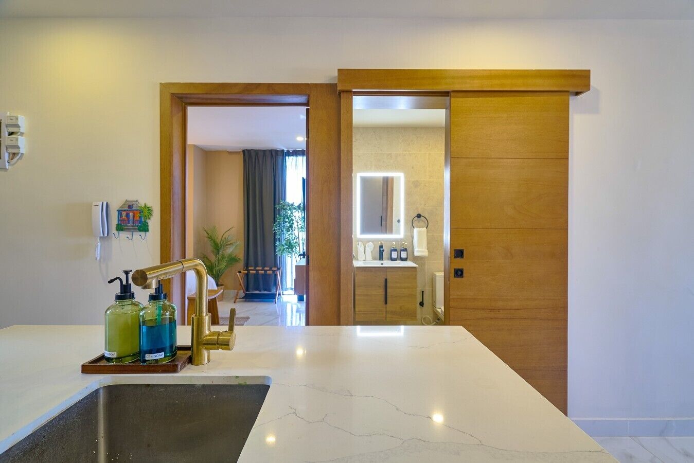 Une salle de bain moderne avec un lavabo en marbre, un robinet doré et deux distributeurs de savon.