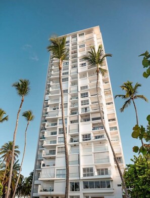 A tall, multi-story hotel with balconies and palm trees. - FrontBeach Apt Pool AC Juan Dolio Beach Aquarella (Playa Juan Dolio)