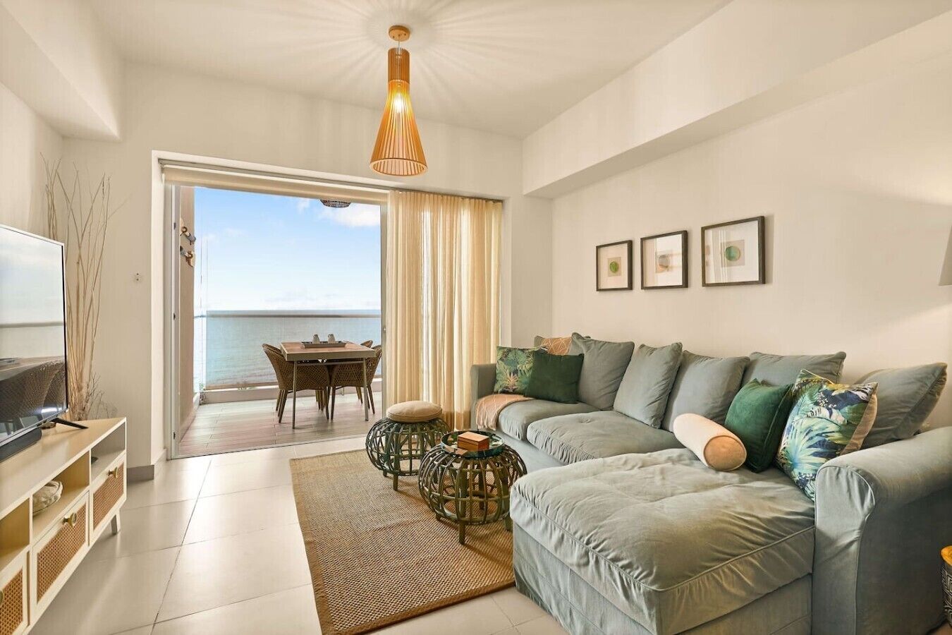 Una sala de estar moderna con un sofá, una televisión, una mesa de comedor y vista al mar.