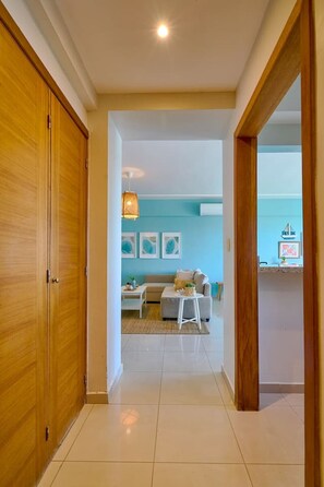 A hallway leading to a living area with a sofa, a coffee table, and wall art. - Tropical BeachSide Apartment 4PAX AC La Velas (Playa Juan Dolio)