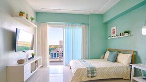 Ein Schlafzimmer mit einem Bett, einem Fernseher, einem Schreibtisch und einem Balkon mit Blick.