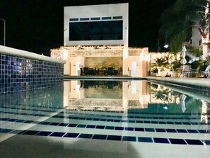 Une piscine avec un sol carrelé et un bâtiment en arrière-plan.