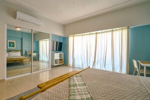 Ein Schlafzimmer mit einem Bett, einem Fernseher, einem Schreibtisch und einem Spiegel.