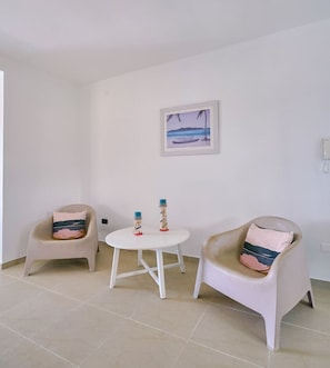 A room with two chairs, a small round table, and a wall-mounted phone. - BeachsideGetaway|3BR|Pool|5Min walk to Beach|Wi-Fi (Juan Dolio)