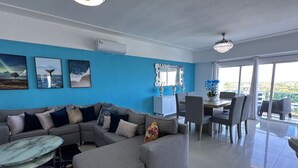 En moderne stue med en hjørnesofa, et spiseområde med en lysekrone og kunst på væggene.