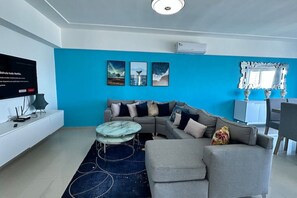 A modern living room with a sectional sofa, a round coffee table, and a flat-screen TV. - BeachSide Blue Cleef Playa Juan Dolio Las Velas (Juan Dolio)