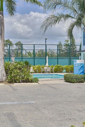 A swimming pool area with a fenced deck, palm trees, and a small pavilion. - BeachSide Blue Cleef Playa Juan Dolio Las Velas (Juan Dolio)